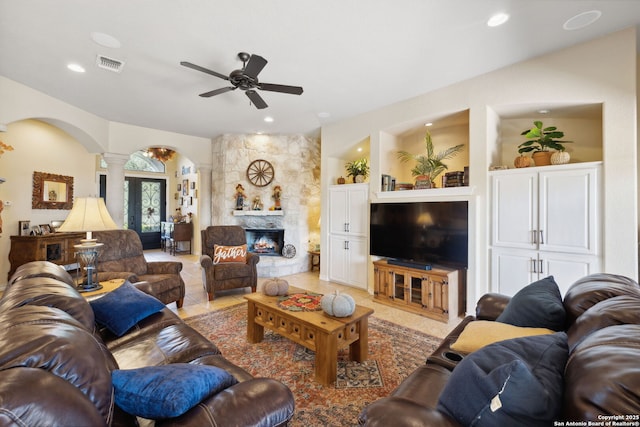 tiled living room featuring ceiling fan, a fireplace, and ornate columns