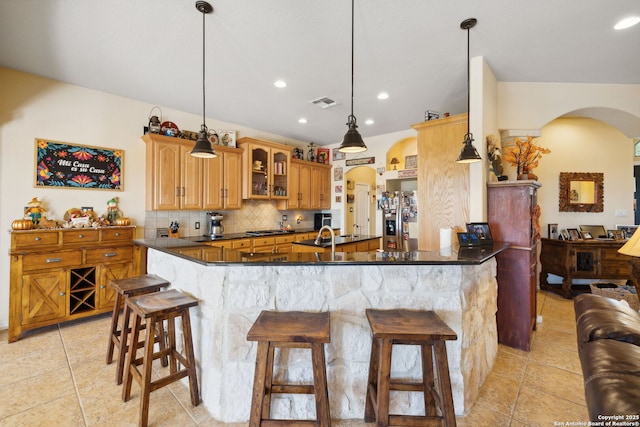 kitchen featuring pendant lighting, backsplash, kitchen peninsula, and a kitchen bar