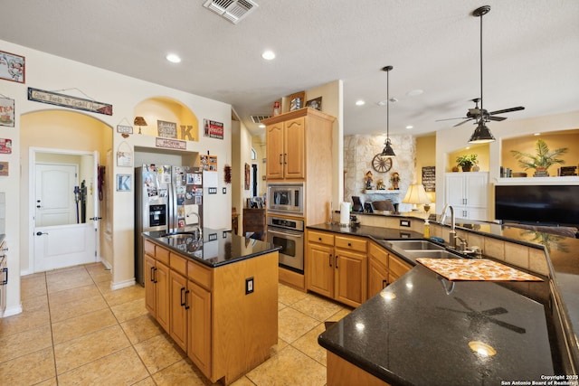 kitchen with stainless steel appliances, an island with sink, sink, and pendant lighting