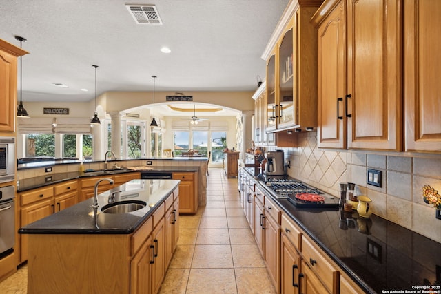 kitchen with ornate columns, pendant lighting, sink, a kitchen island with sink, and kitchen peninsula