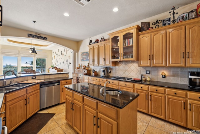 kitchen with a kitchen island with sink, sink, hanging light fixtures, and appliances with stainless steel finishes