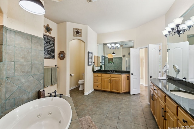 bathroom featuring a notable chandelier, vanity, tile patterned floors, and a tub