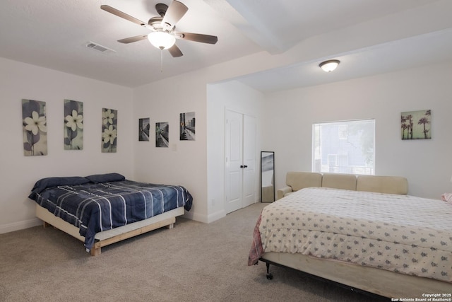 carpeted bedroom featuring ceiling fan, beam ceiling, and a closet