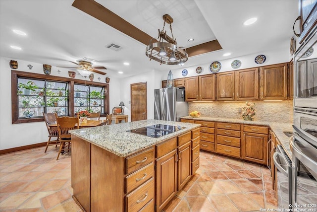 kitchen with a kitchen island, decorative light fixtures, stainless steel fridge, decorative backsplash, and black electric cooktop