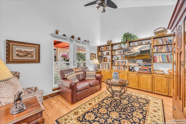 living room featuring light hardwood / wood-style flooring, ceiling fan, and a high ceiling