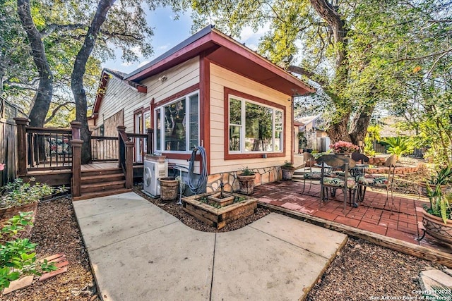 rear view of property with a deck, a patio, and ac unit