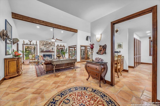 living room featuring ceiling fan, a stone fireplace, and lofted ceiling with beams