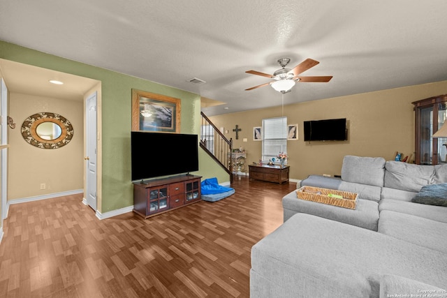 living room featuring hardwood / wood-style flooring, ceiling fan, and a textured ceiling