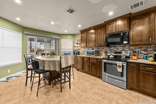 kitchen with appliances with stainless steel finishes, light stone counters, and decorative backsplash