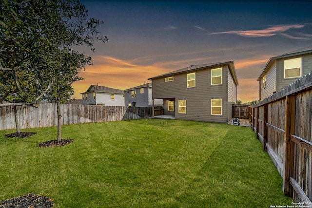 back house at dusk with a lawn