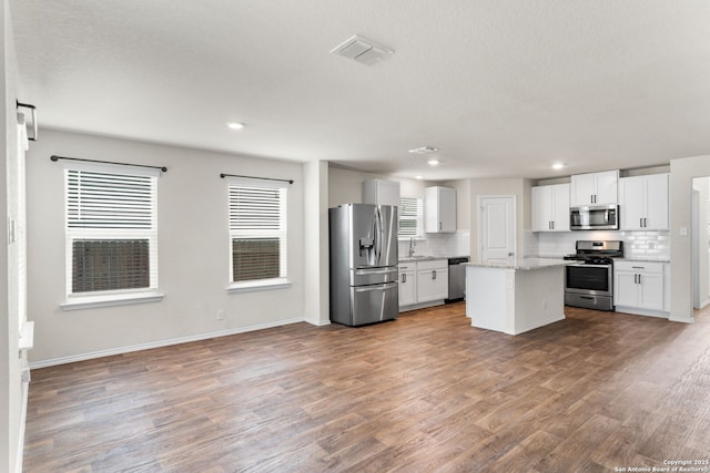 kitchen featuring decorative backsplash, a kitchen island, white cabinets, and appliances with stainless steel finishes