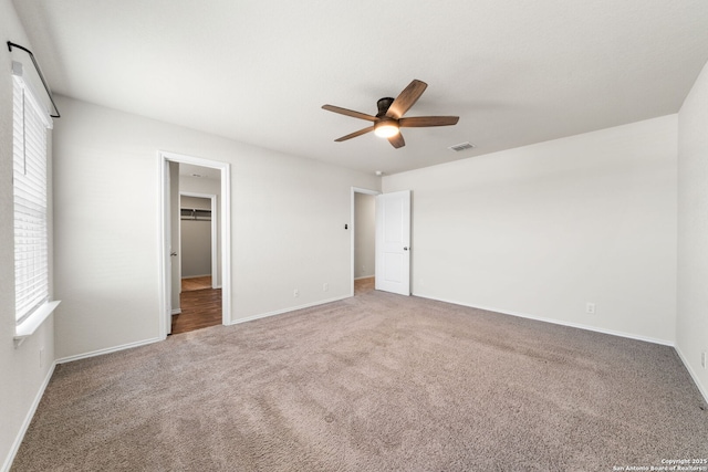 unfurnished bedroom with ceiling fan, carpet, and a walk in closet