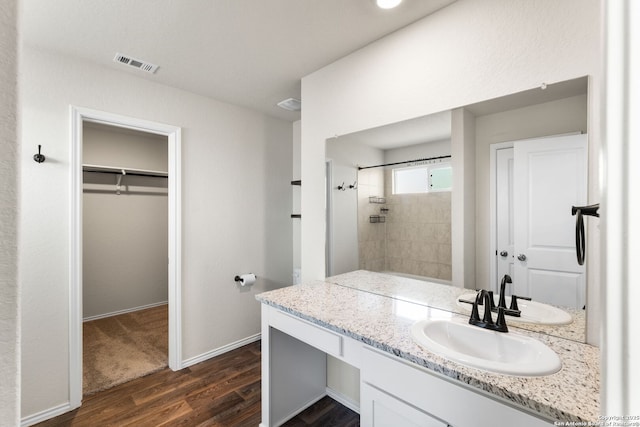 bathroom featuring hardwood / wood-style flooring, vanity, and tiled shower