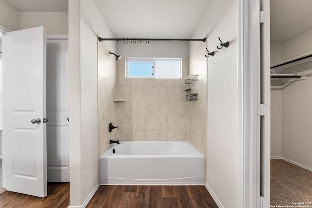 bathroom featuring wood-type flooring and tiled shower / bath