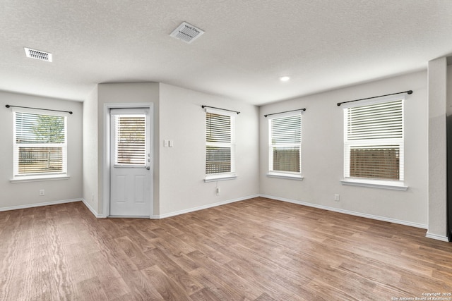 unfurnished room featuring a textured ceiling and light wood-type flooring