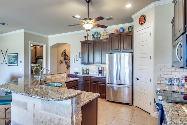 kitchen featuring stainless steel appliances, sink, a center island with sink, and dark brown cabinetry