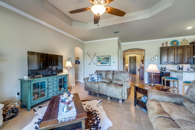 living room featuring a tray ceiling, ornamental molding, ceiling fan, and light tile patterned flooring