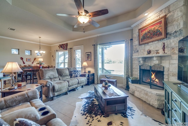 living room with a raised ceiling, ornamental molding, light tile patterned floors, and a fireplace