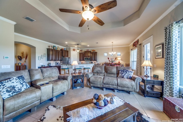 living room with ornamental molding, a tray ceiling, and light tile patterned floors