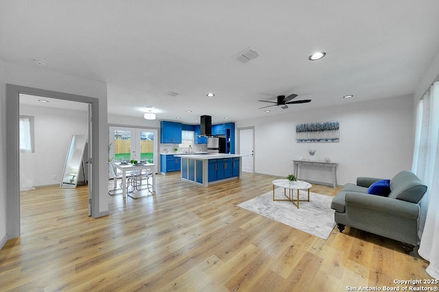 living room featuring sink, light hardwood / wood-style floors, french doors, and ceiling fan