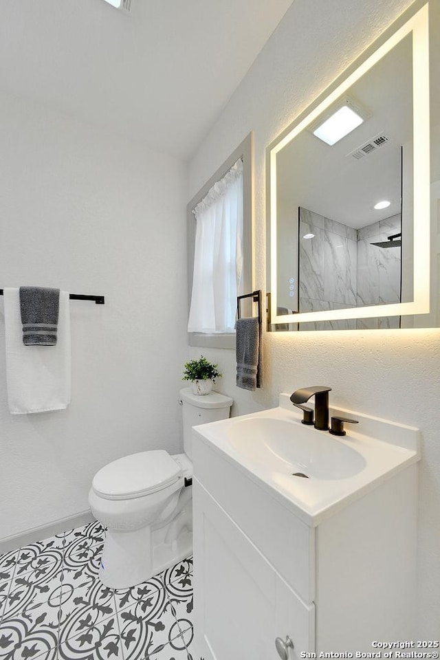 bathroom with walk in shower, vanity, and toilet