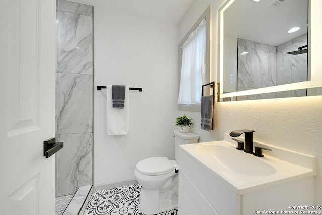 bathroom featuring vanity, tiled shower, and toilet