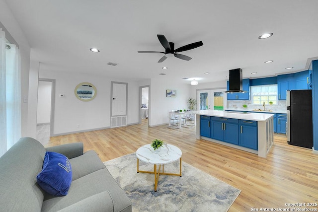 living room featuring ceiling fan, sink, and light wood-type flooring