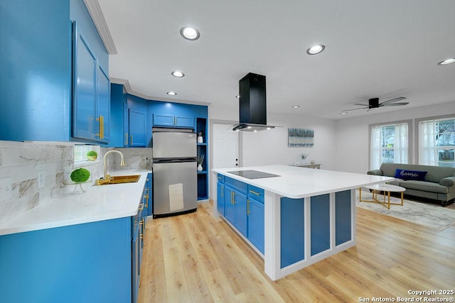 kitchen featuring blue cabinetry, sink, stainless steel fridge, island exhaust hood, and black electric stovetop