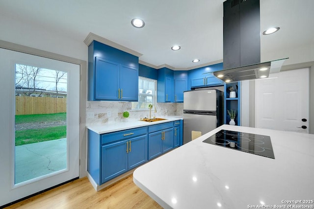 kitchen featuring sink, stainless steel fridge, blue cabinetry, and island exhaust hood