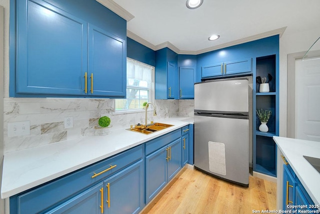 kitchen with stainless steel refrigerator, blue cabinetry, sink, and light hardwood / wood-style flooring