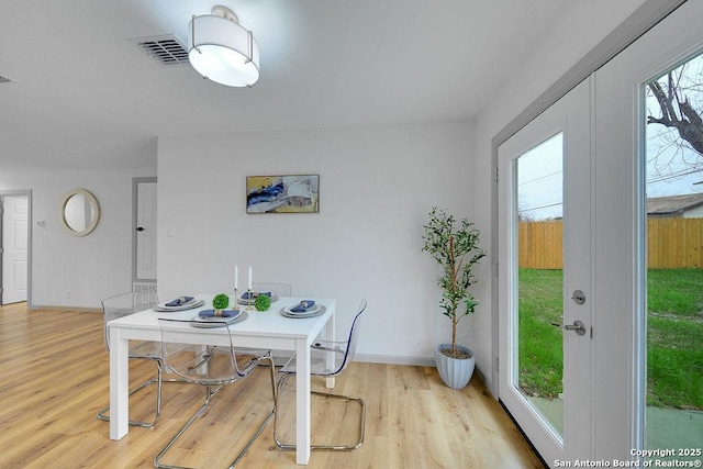 dining room featuring a healthy amount of sunlight, light hardwood / wood-style floors, and french doors