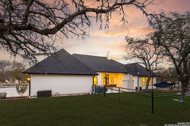 back house at dusk featuring a yard