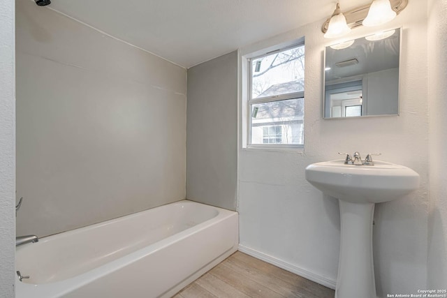 bathroom with a tub to relax in and hardwood / wood-style floors