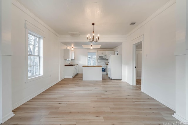 unfurnished living room with crown molding, sink, a chandelier, and light wood-type flooring