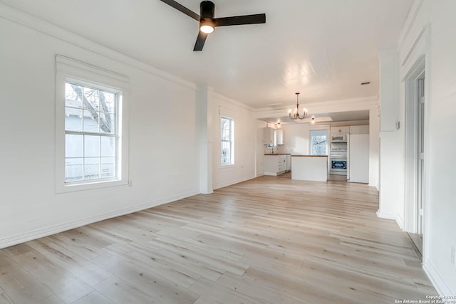 unfurnished living room featuring ornamental molding, ceiling fan with notable chandelier, and light hardwood / wood-style floors