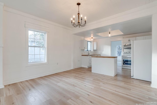 kitchen with electric range oven, white cabinetry, white refrigerator, hanging light fixtures, and light hardwood / wood-style flooring