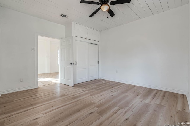 unfurnished bedroom with ceiling fan, a closet, light hardwood / wood-style flooring, and wooden ceiling