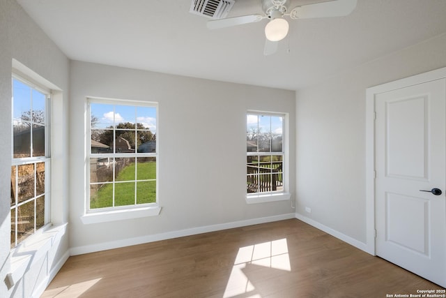 spare room with ceiling fan, plenty of natural light, and hardwood / wood-style floors
