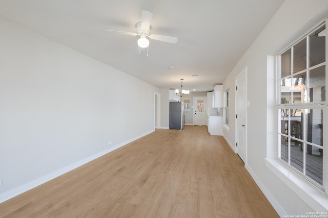 unfurnished living room with ceiling fan with notable chandelier and light wood-type flooring