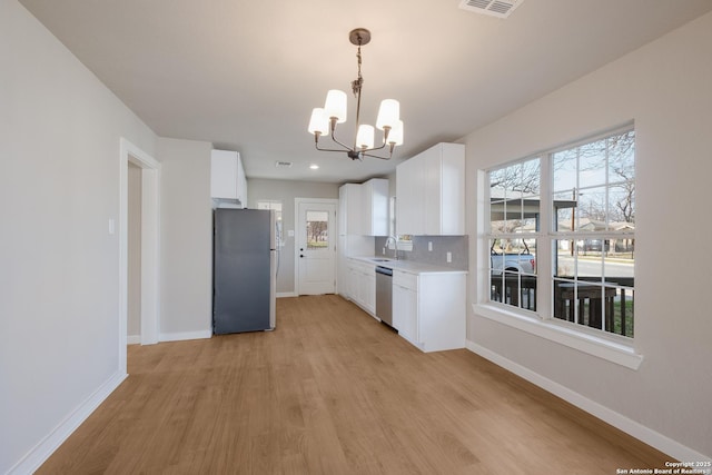 kitchen featuring sink, light hardwood / wood-style flooring, white cabinetry, stainless steel appliances, and tasteful backsplash