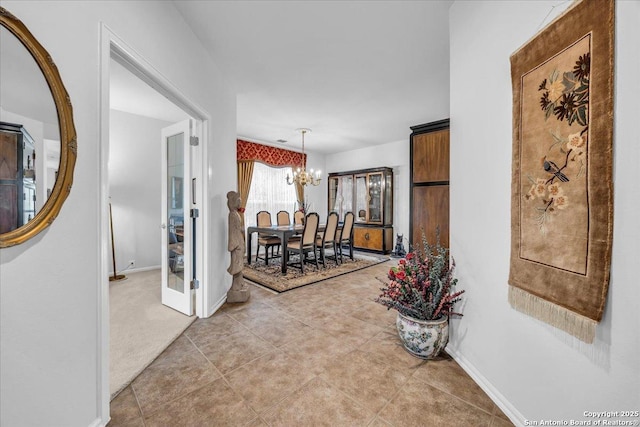 hall with tile patterned floors and a chandelier