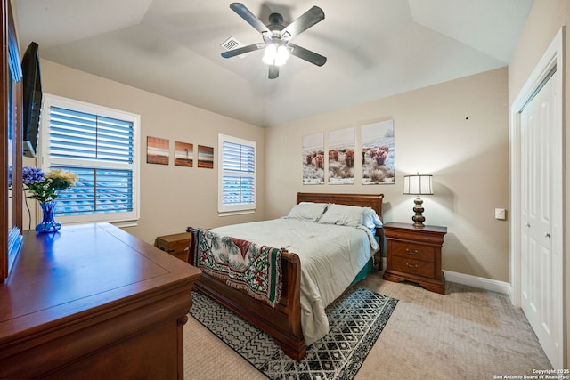 carpeted bedroom with lofted ceiling, a raised ceiling, a closet, and ceiling fan