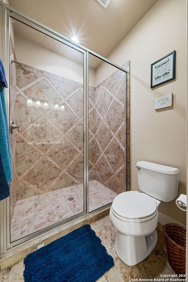 bathroom with a shower with shower door and toilet