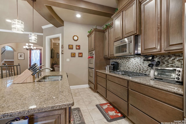 kitchen featuring stainless steel appliances, light stone countertops, sink, and decorative backsplash