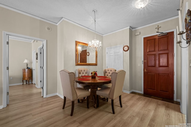 dining area with ornamental molding, an inviting chandelier, a textured ceiling, and light wood-type flooring