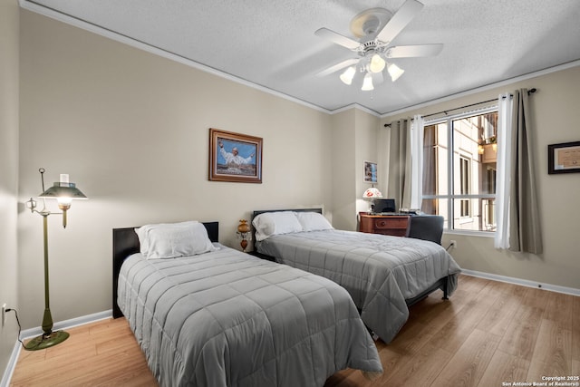 bedroom with ceiling fan, ornamental molding, light hardwood / wood-style floors, and a textured ceiling