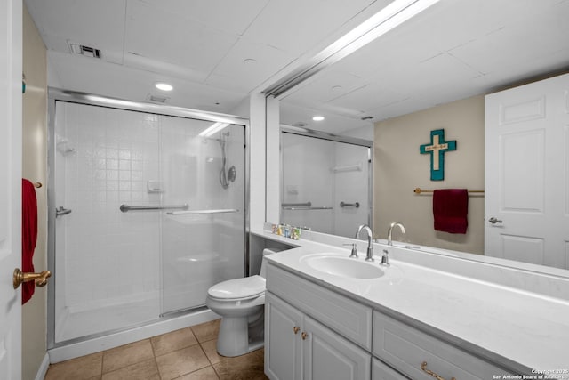 bathroom with tile patterned flooring, vanity, a shower with door, and toilet