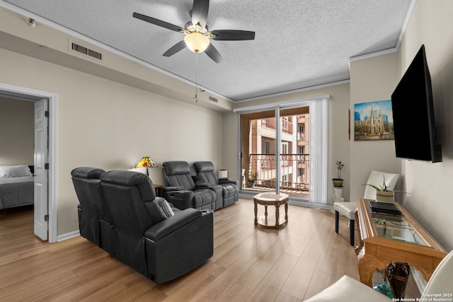 living room with crown molding, ceiling fan, a textured ceiling, and light wood-type flooring