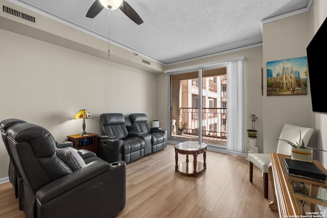 living room featuring ceiling fan, light hardwood / wood-style floors, and a textured ceiling