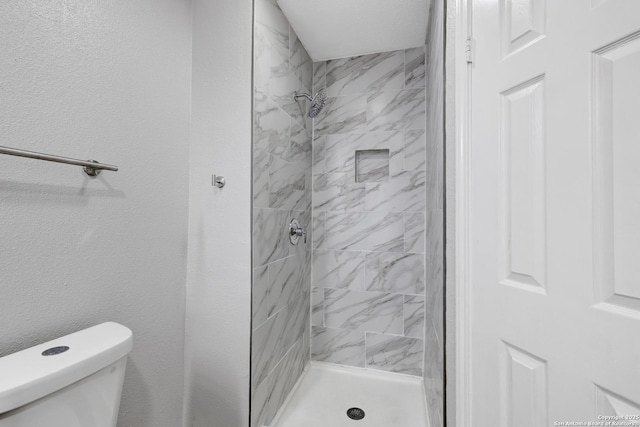 bathroom featuring a tile shower and toilet